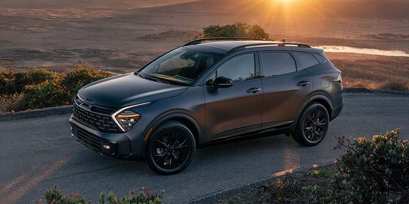 Gray Kia Sportage Hybrid SUV parked at sunset.