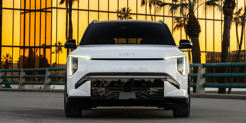 2027 Kia EV3 electric SUV parked near a modern building at sunset.