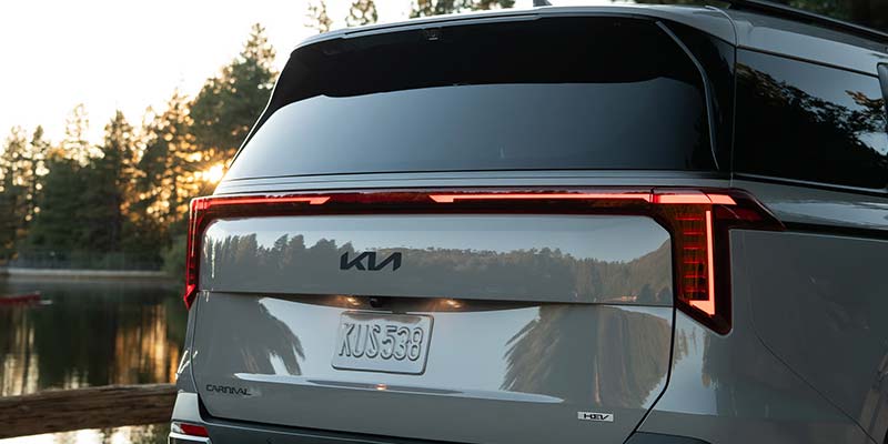 Rear view of a Kia vehicle parked near a lake at sunset
