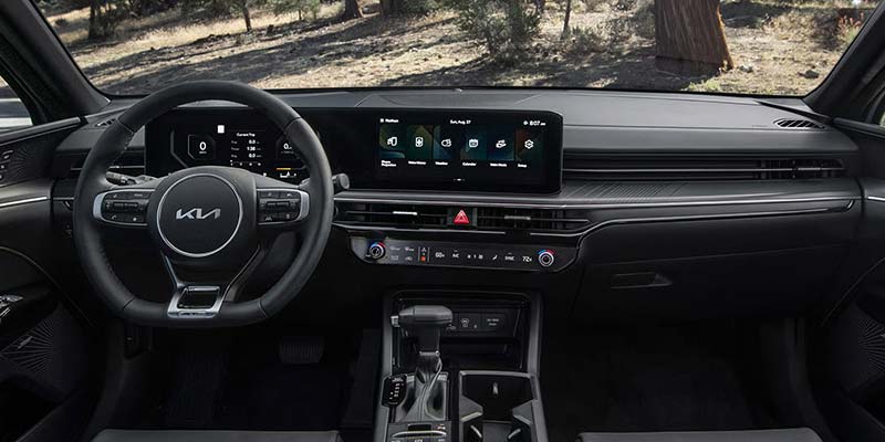 Car interior showcasing the steering wheel, dashboard, and wide touchscreen display.